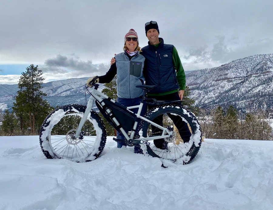 two people posing for a picture next to a snowy bike