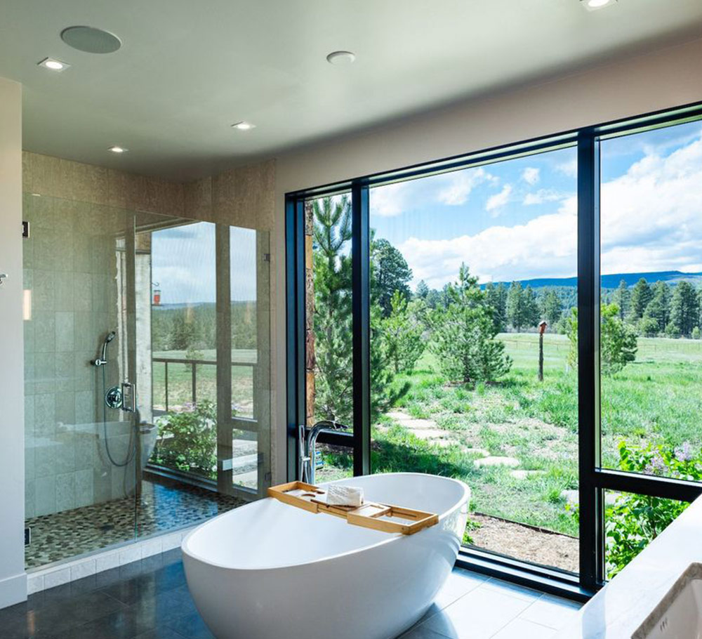 a well-lit bathroom showcasing a large window that overlooks the outdoor scenery, blending indoor comfort with nature